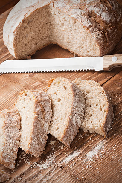 Bread slices Brown bread slices (can be black wheat, or oat), with bread knife on the wooden plank as background; Adobe rgb color space serrated stock pictures, royalty-free photos & images