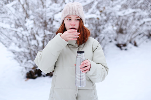 a girl pours tea from a thermos on a frosty winter day