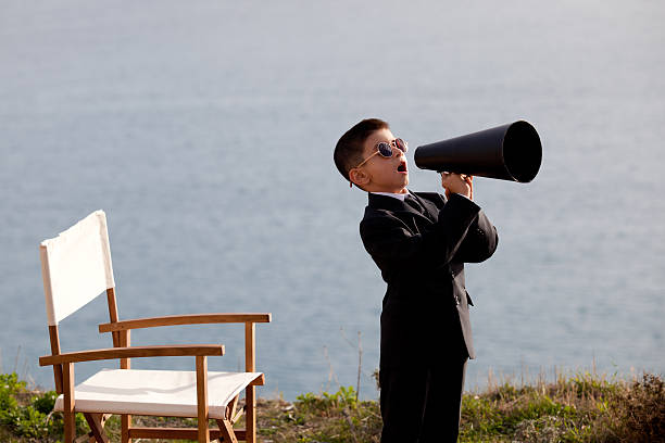 istock Young boy dressed in a smart suit acting like film director 185007313