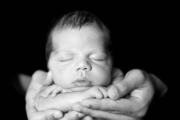 istock Black and White Image of Newborn Sleeping in Father's Hands 185007367