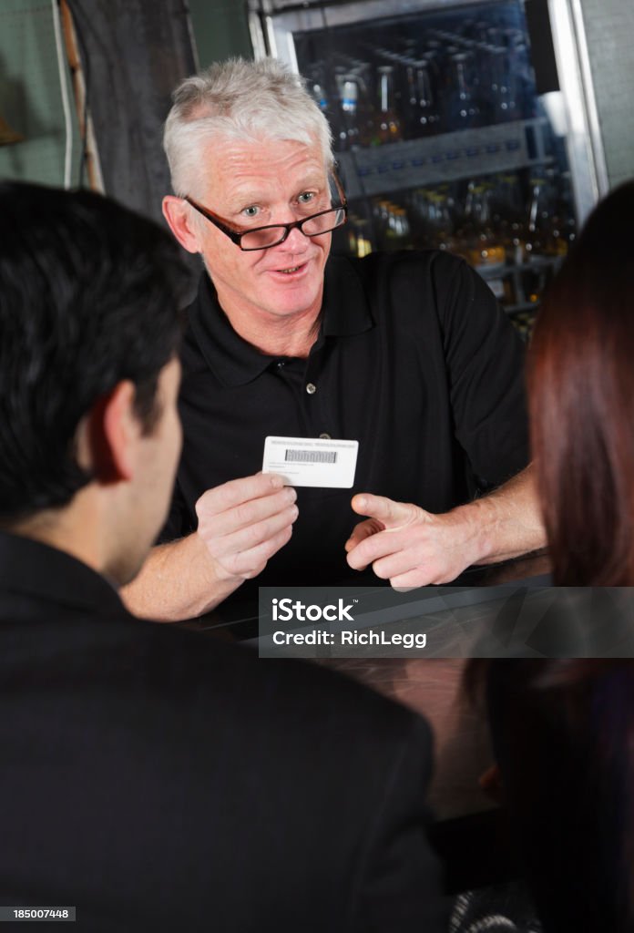 Bartender Checking ID A bartender checking the ID of a customer. ID Card Stock Photo