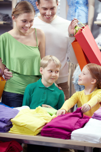 Smiling young parent choosing clothes for their children