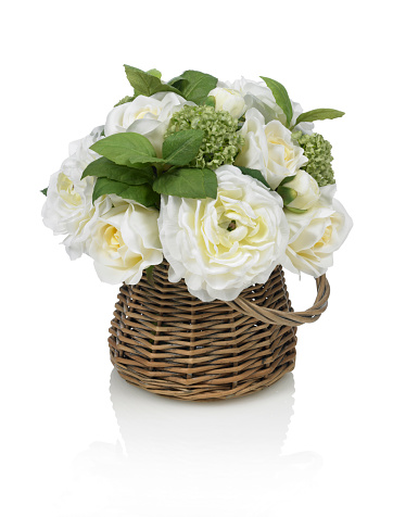 An adorable mixed bouquet of white roses and ranunculus in a wicker garden basket. Shot against a bright white background. There is a path which may be used to delete the reflection if desired. Extremely high quality faux flowers.