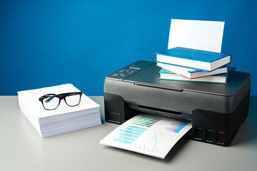 Laser printer on desk against blue background close up