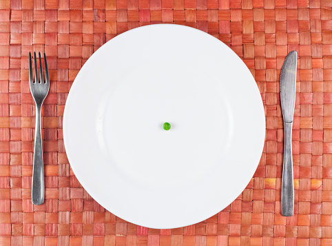 A single pea on a white plate