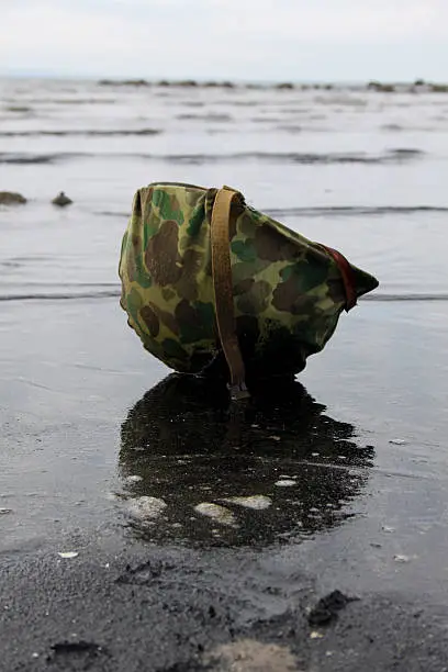 WW2 US Marine's helmet lies on Iwo Jima beach.Re-enactment.