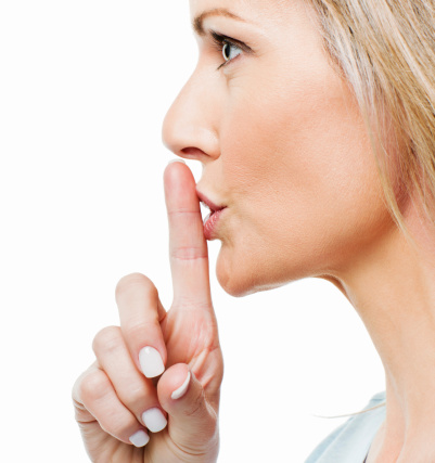 Profile of a woman gesturing for silence with a finger to her lips. Horizontal shot.