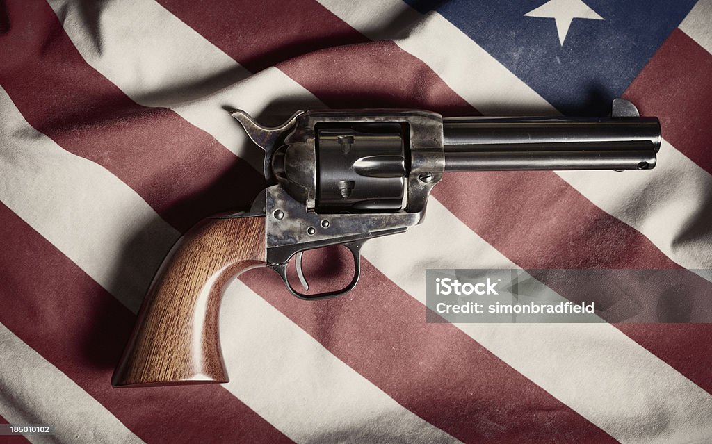 Colt Peacemaker "The legendary six-shooter from the Wild West, the Colt Peacemaker, sitting on top of an American flag." Flag Stock Photo