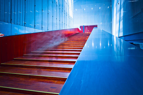 Grand, polished stone staircase with multiple tiers, curved handrails, and ample natural light from tall windows Marble or similar material on walls, soft shadows, no people or text present