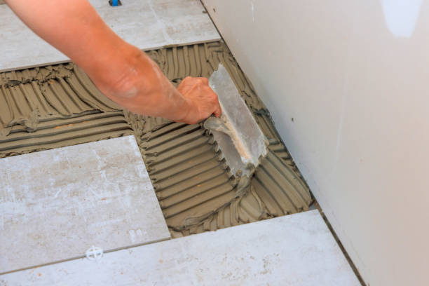 istock Troweling adhesive onto a concrete floor in preparation for laying floor tile. 1850110497