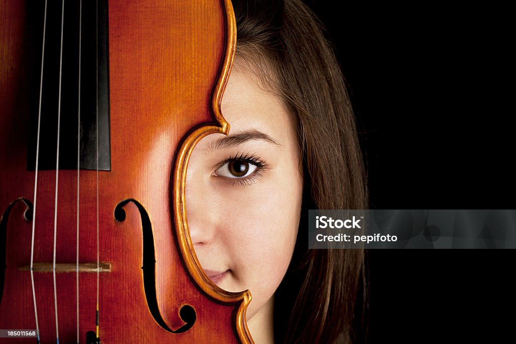 Peeking young girl with violin isolated on black background Art Stock Photo