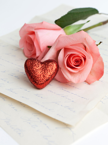 Red heart and pink roses on old love letters for Valentine's Day.
