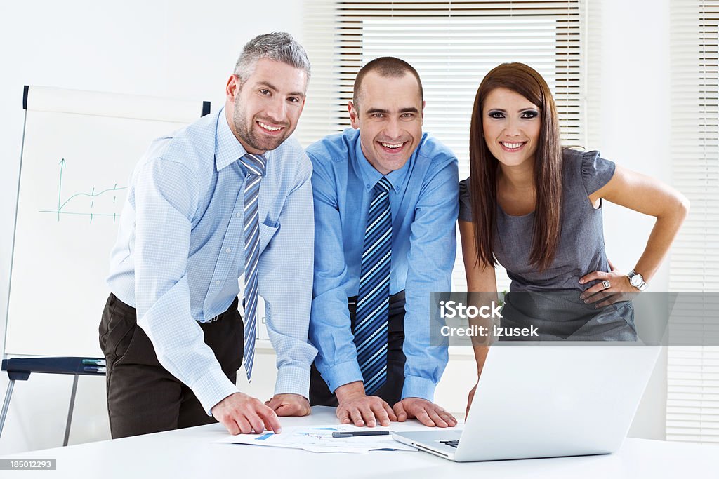 Business people at work Three business people working on project in meeting room, smiling at camera. 25-29 Years Stock Photo