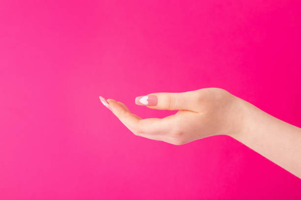 istock female hands with beautiful long nails with  manicure with  heart pattern on pink background 1850123626