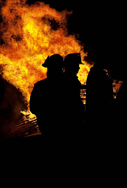 istock silhouette of  firemen with flames in background 185012903