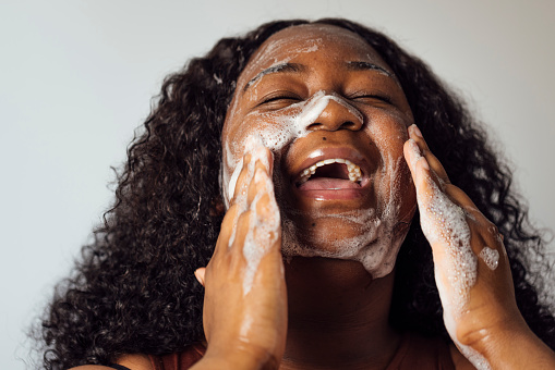Close-up portrait of a mid adult woman applying a cleansing scrub to her face.