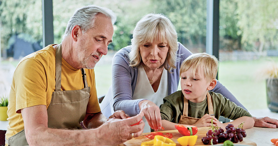 Healthy, grandparents or child cooking for lunch, vegetables or nutrition with love in family home. Fruits, senior grandfather or kid with elderly grandma, care or food for diet, teaching or learning