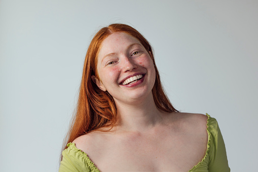 Close-up portrait of a young female adult looking at the camera and smiling.