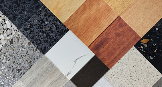 swatches and palette of material samples contains wooden veneer, ceramic stone tiles, quartz marbles, terrazzo, artificial stones in close up view. multi texture and color of interior materials.