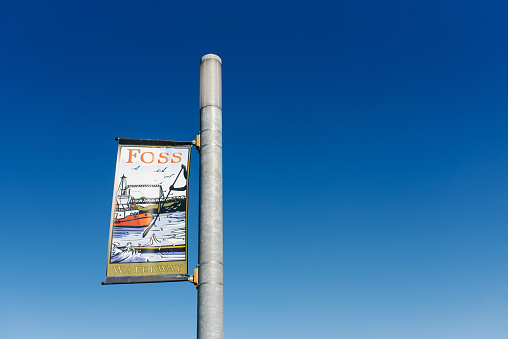 Tacoma, Washington, USA. A banner with the inscription Foss Waterway on the lighting mast against the blue sky