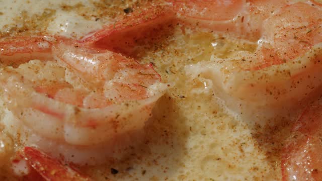 Shrimps in a creamy sauce with garlic and lime juice are languishing in a frying pan. Traditional Asian Mexican Thai dish. High quality studio shot macro close-up. Cooking Italian pasta.