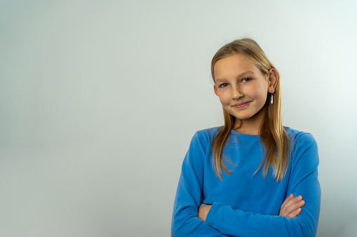 8 years old girl standing against blue background.