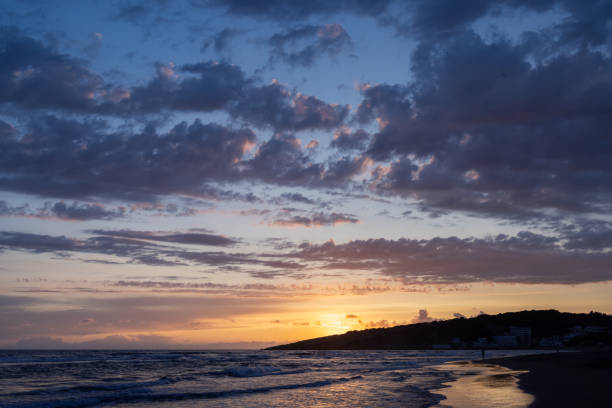 istock Sunset on the sea, dark ragged clouds, waves rolling on the sandy shore 1850208481