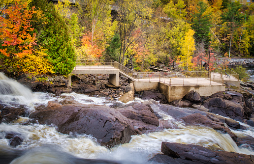 Bracebridge Falls runs into Muskoka River with Trans Canada Trail and autumn foliage colors in Ontario, Canada