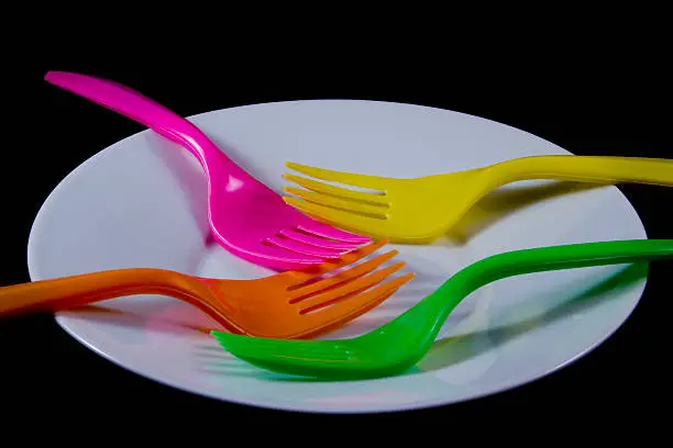 Four colorized forks in white plate isolated