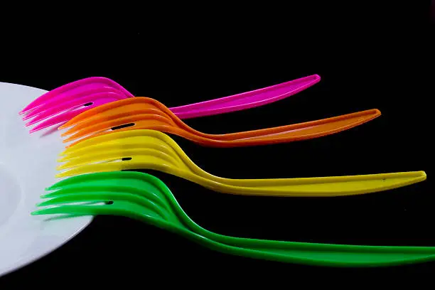 Four colorized forks in white plate isolated