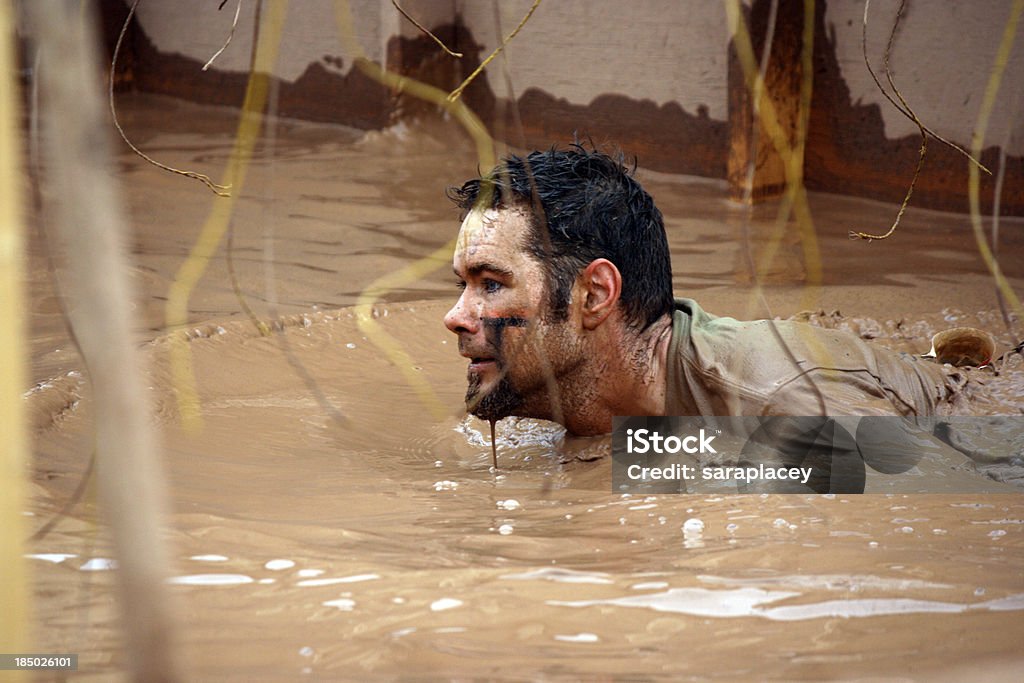 man at mud run obstacle course A man is submerged in mud and going through the electric shock part of an obstacle course event Mud Run Stock Photo