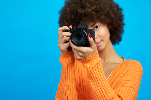 Portrait of a photographer covering her face with her camera while taking a picture