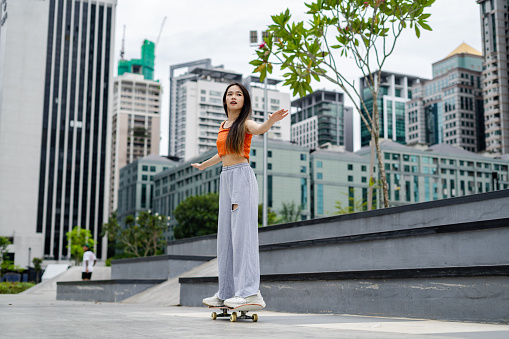 young woman practicing skateboarding in city skateboarding park, active lifestyle concepts