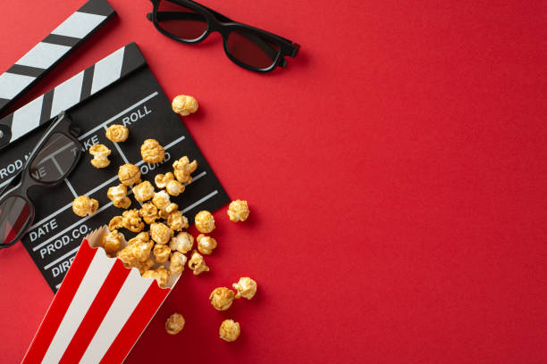 istock Valentine's Cinema Magic: Overhead composition with a clapperboard, 3D glasses, popcorn in striped container on a vibrant red surfaceâa captivating atmosphere for a romantic film debut 1850294170