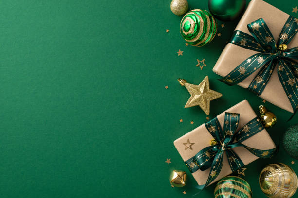 istock Luxurious festive display. Overhead perspective of handcrafted paper gift boxes, ornate baubles, sparkling star ornament, gold confetti arranged on a green surface, offering space for promotional text 1850294367