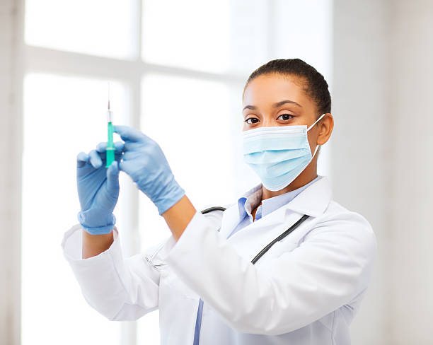 istock african doctor holding syringe with injection 185029657