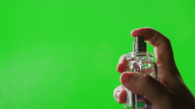 Young man applying perfume to skin on chroma key green screen, close up of spraying deodorant luxury perfume.