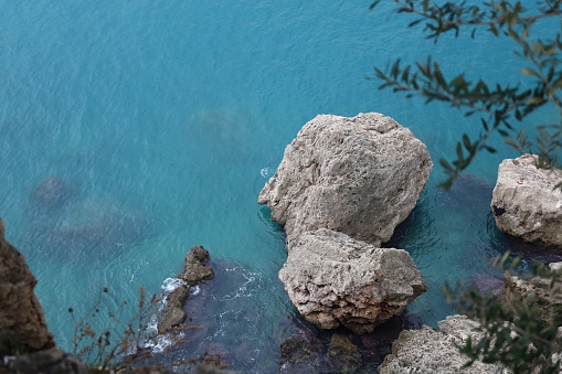 The deep blue sea of ​​the Mediterranean and big stones in Antalya, Turkiye.