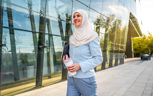 Cheerful mature Muslim businesswoman in front of an office building