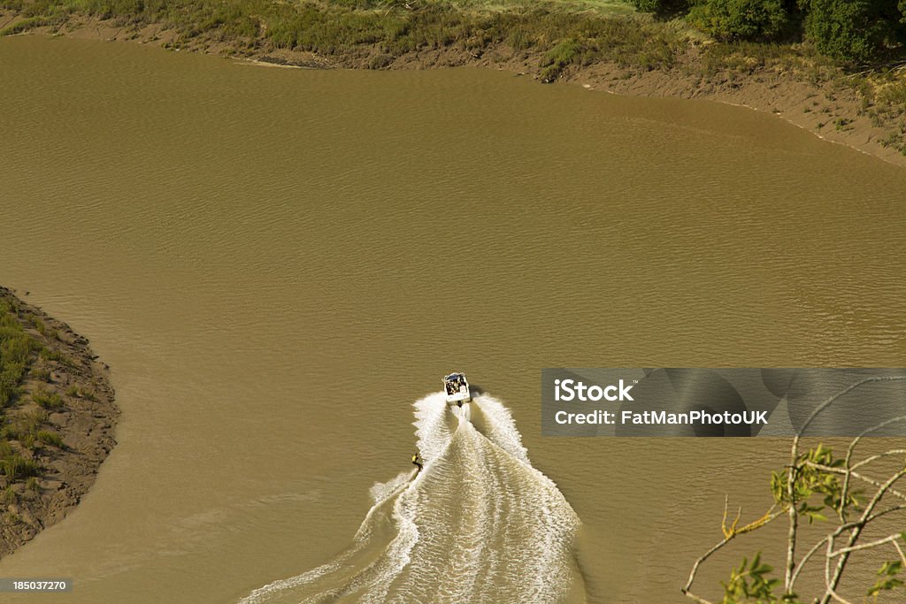 Water Skiing on the River Wye, Wintour's Leap. Water skiing on the brown, tidal River Wye from the limestone cliffs of Wintourâs Leap, at Woodcroft, Gloucestershire, England, United Kingdom. Aquatic Sport Stock Photo