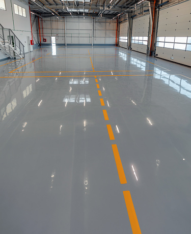 This image shows a large industrial warehouse with a glossy epoxy paint covering the floors