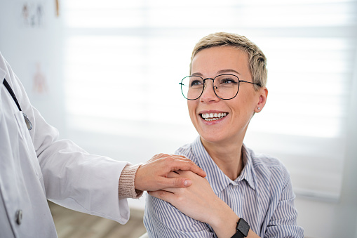 Medical practitioner showing support to a female patient, touching her shoulder