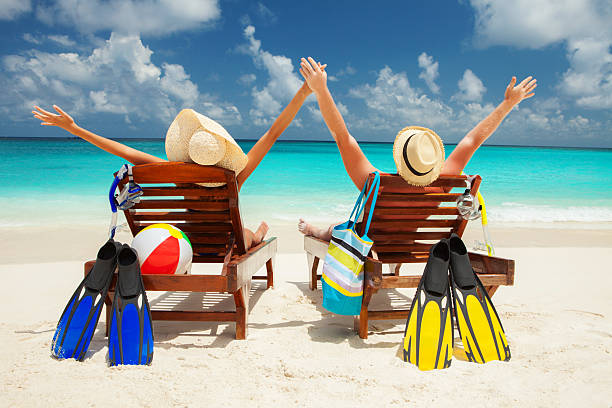 Couple sitting on beach with arms raised