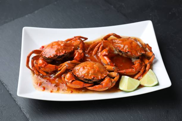 istock Delicious boiled crabs with sauce and lime on black textured table 1850418378