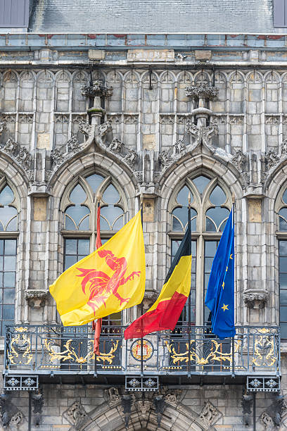 Flags waving on City Hall building facade in Mons, capital of the Wallonian province of Hainaut in Belgium.