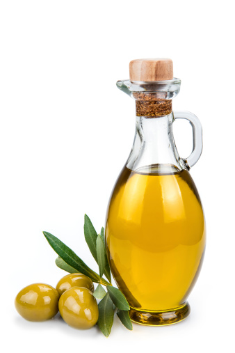 Olive oil in a glass bottle and green olives isolated over a white background