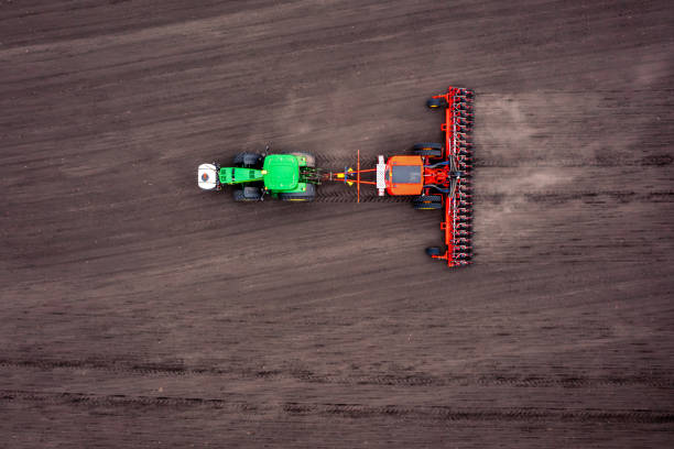 Tractor cultivating the soil during springtime seen from above during a sunny and dry springtime day. Aerial view drone view from directly above.