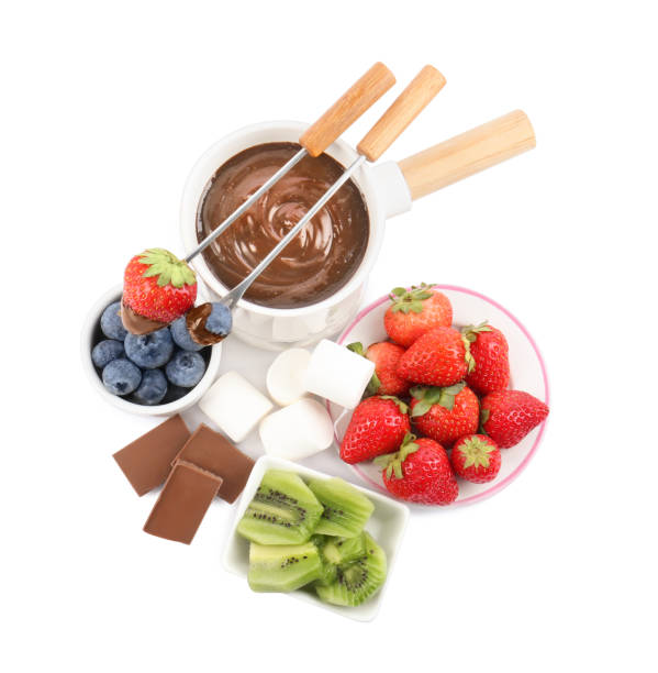 istock Fondue pot with melted chocolate, fresh berries, kiwi, marshmallows and forks isolated on white 1850437827