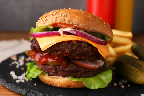 istock Tasty cheeseburger with patties, onion and pickles on table, closeup 1850456796