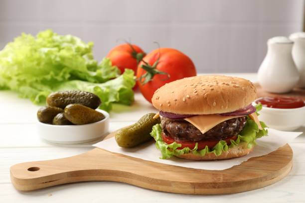 istock Tasty hamburger with patty, cheese and vegetables served on table 1850456931